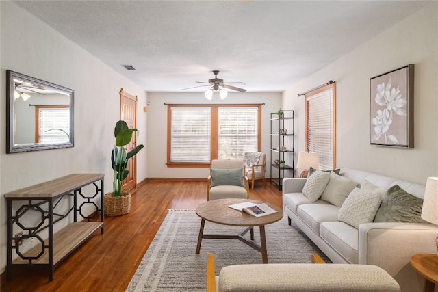 living area with ceiling fan, baseboards, wood finished floors, and visible vents