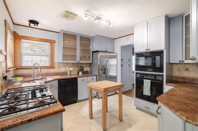 kitchen featuring visible vents, a sink, glass insert cabinets, black appliances, and tasteful backsplash