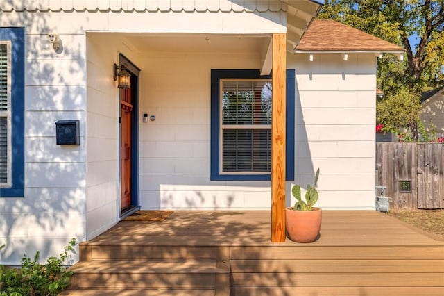 entrance to property with fence and a shingled roof