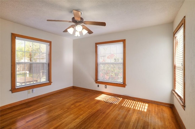 spare room featuring wood finished floors, a textured ceiling, baseboards, and ceiling fan