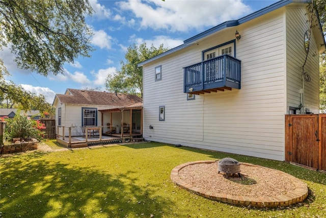 rear view of property featuring a fenced backyard, a balcony, and a lawn