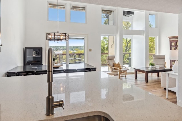 interior space featuring an inviting chandelier, hanging light fixtures, light stone countertops, and a towering ceiling