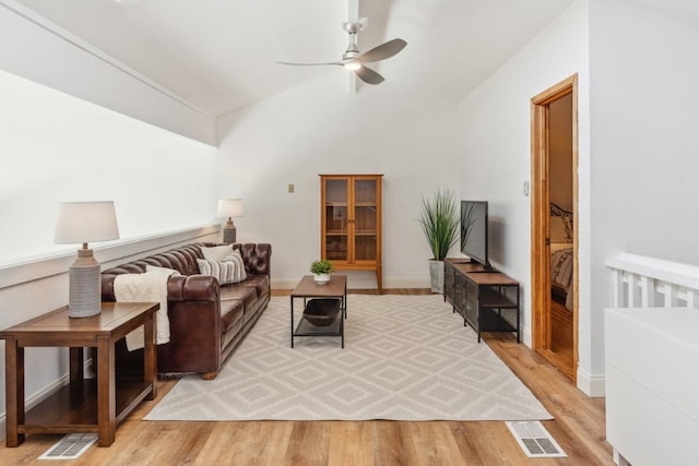 living room featuring light wood-type flooring, vaulted ceiling, visible vents, and ceiling fan