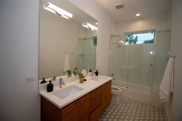 bathroom with shower / bath combination with glass door, toilet, a sink, and double vanity