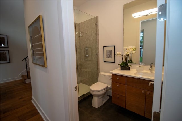 bathroom with toilet, baseboards, wood finished floors, a shower stall, and vanity