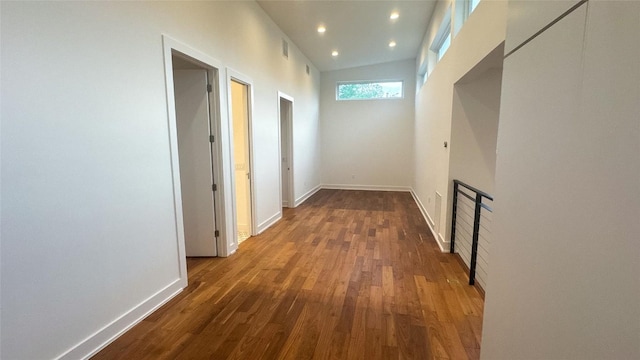 hallway with lofted ceiling, baseboards, wood finished floors, and recessed lighting