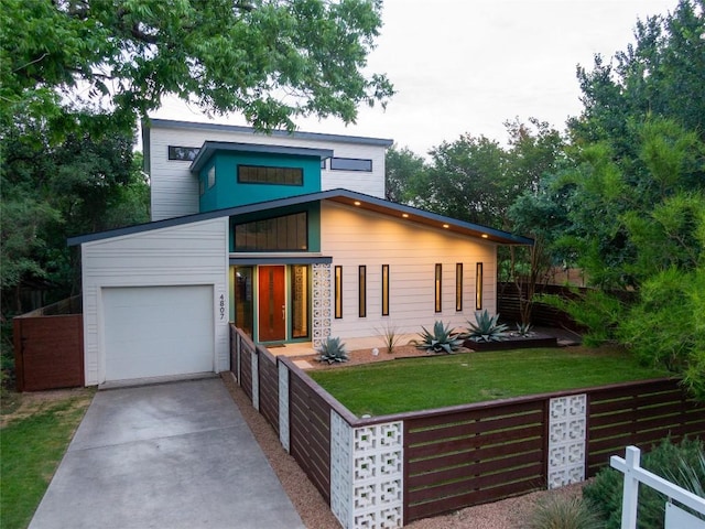 contemporary home with concrete driveway, an attached garage, and a front lawn