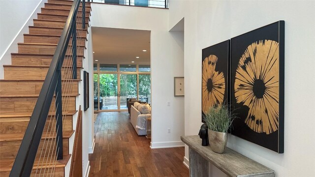 corridor with recessed lighting, stairway, wood finished floors, baseboards, and expansive windows
