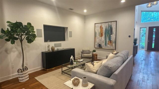 living room featuring visible vents, baseboards, wood finished floors, and recessed lighting