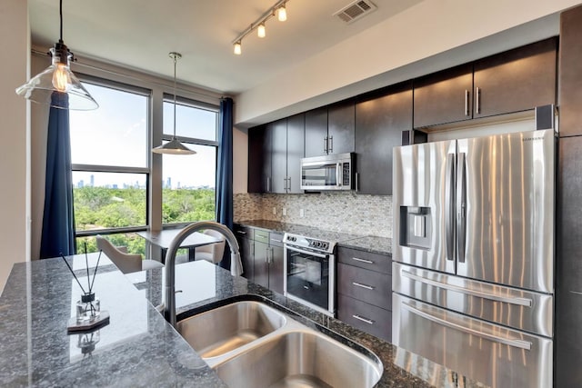 1320 Robert Browning St Unit 409, Austin, TX 78723 - kitchen featuring stainless steel appliances, a sink, backsplash, pendant lighting, and dark stone countertops
