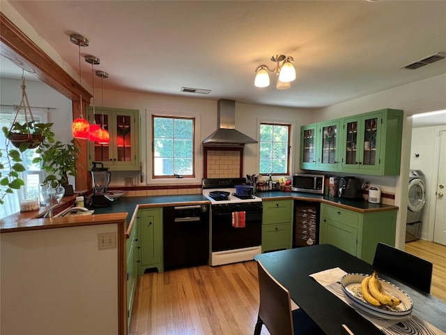 kitchen with green cabinetry, wall chimney range hood, stainless steel microwave, gas range, and black dishwasher
