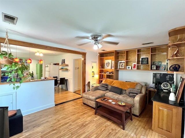 living room with light wood finished floors, visible vents, and ceiling fan