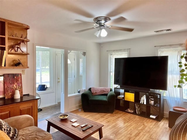 living area featuring a ceiling fan, visible vents, a wealth of natural light, and light wood-style floors