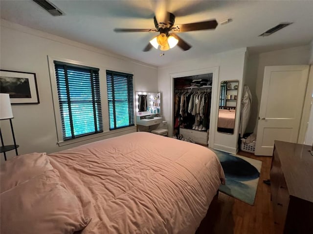 bedroom with wood finished floors, visible vents, a closet, and a ceiling fan