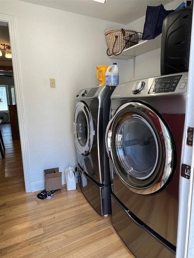 laundry area with washing machine and clothes dryer, laundry area, and light wood finished floors