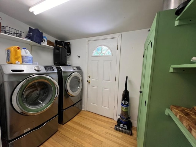 clothes washing area with light wood-style flooring, washer and clothes dryer, and laundry area