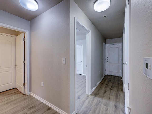6709 Doyal Dr, Austin, TX 78747 - hallway with light wood-style floors, baseboards, and a textured wall