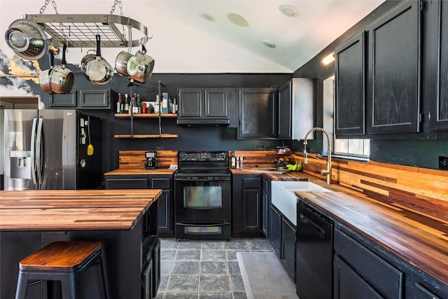 358 Easley Rd, Smithville, TX 78957 - kitchen with wooden counters, black appliances, lofted ceiling, under cabinet range hood, and dark cabinets