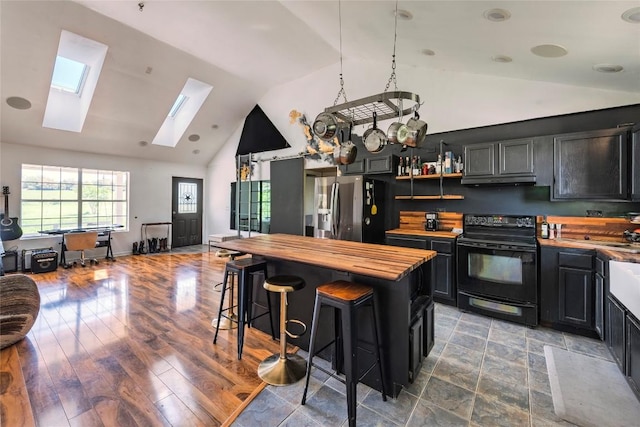 358 Easley Rd, Smithville, TX 78957 - kitchen with black electric range oven, stainless steel fridge with ice dispenser, butcher block countertops, a skylight, and dark cabinetry