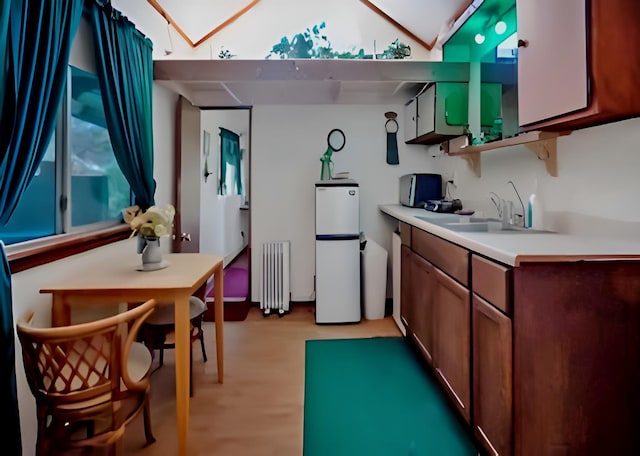 kitchen with radiator, light countertops, open shelves, a sink, and light wood-style flooring