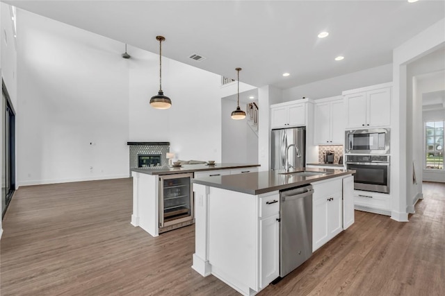 2616 War Wagon Way, Leander, TX 78641 - kitchen with stainless steel appliances, dark countertops, beverage cooler, light wood finished floors, and recessed lighting