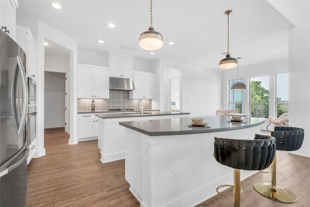 2616 War Wagon Way, Leander, TX 78641 - kitchen featuring an island with sink, stainless steel appliances, under cabinet range hood, decorative backsplash, and recessed lighting