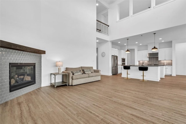 2616 War Wagon Way, Leander, TX 78641 - living area featuring light wood-style flooring, a towering ceiling, a fireplace, and recessed lighting