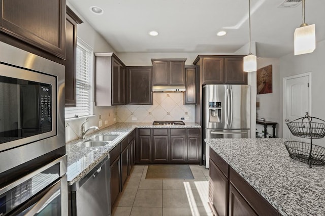5679 Corsica Loop, Round Rock, TX 78665 - kitchen featuring appliances with stainless steel finishes, dark brown cabinetry, backsplash, under cabinet range hood, and recessed lighting