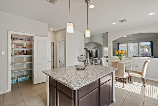 5679 Corsica Loop, Round Rock, TX 78665 - kitchen with arched walkways, light tile patterned floors, dark brown cabinets, decorative light fixtures, and recessed lighting