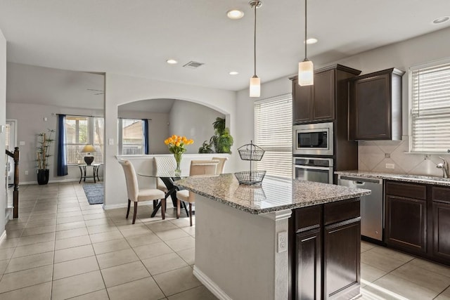 5679 Corsica Loop, Round Rock, TX 78665 - kitchen featuring stainless steel appliances, dark brown cabinets, light tile patterned flooring, decorative backsplash, and recessed lighting
