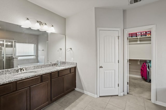 5679 Corsica Loop, Round Rock, TX 78665 - bathroom with a stall shower, a bath, tile patterned flooring, a spacious closet, and double vanity