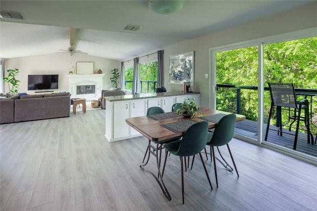 1908 Trevino Dr, Austin, TX 78746 - dining room with ceiling fan, light wood-style floors, a glass covered fireplace, and lofted ceiling