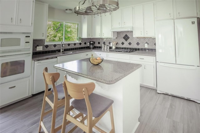 1908 Trevino Dr, Austin, TX 78746 - kitchen with white appliances, a sink, ventilation hood, a breakfast bar area, and tasteful backsplash