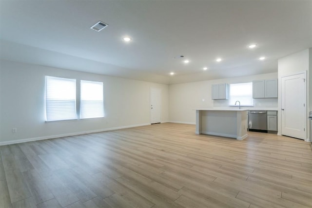 unfurnished living room featuring light wood finished floors, baseboards, and visible vents