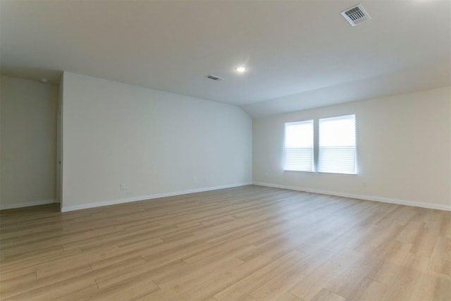 unfurnished room with recessed lighting, light wood finished floors, vaulted ceiling, visible vents, and baseboards