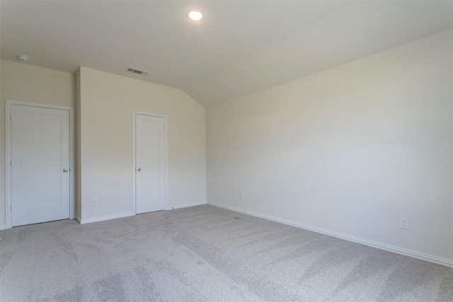 unfurnished bedroom with baseboards, vaulted ceiling, visible vents, and carpet floors