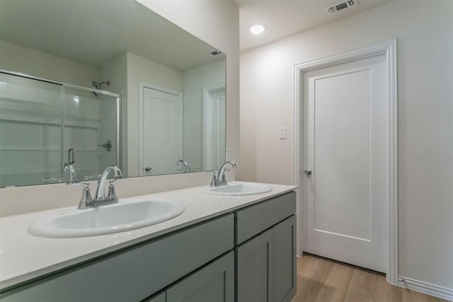 bathroom with a shower stall, visible vents, wood finished floors, and a sink