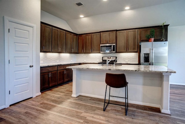 kitchen featuring a sink, stainless steel appliances, visible vents, vaulted ceiling, and dark brown cabinets