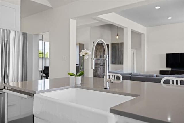 kitchen with white cabinets, open floor plan, a sink, and recessed lighting