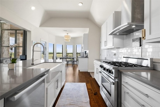 kitchen featuring wall chimney exhaust hood, white cabinets, a sink, dishwashing machine, and stainless steel stove