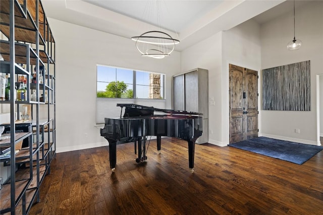 sitting room with a chandelier, baseboards, wood finished floors, and a towering ceiling