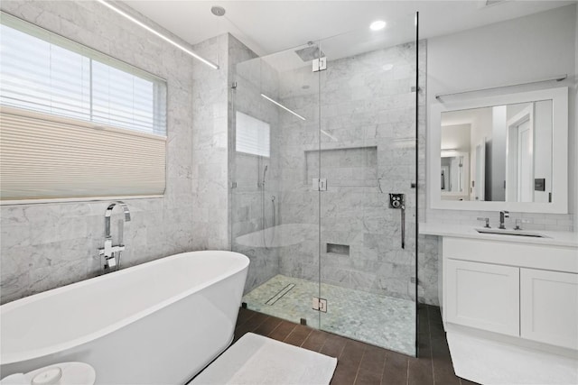 full bathroom with a shower stall, wood finished floors, decorative backsplash, a freestanding tub, and vanity