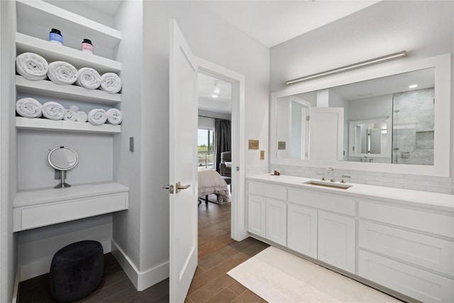bathroom featuring tasteful backsplash, wood finished floors, ensuite bathroom, vanity, and a walk in shower
