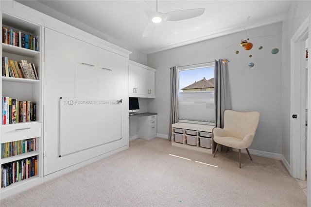 sitting room with built in shelves, ceiling fan, light carpet, and baseboards