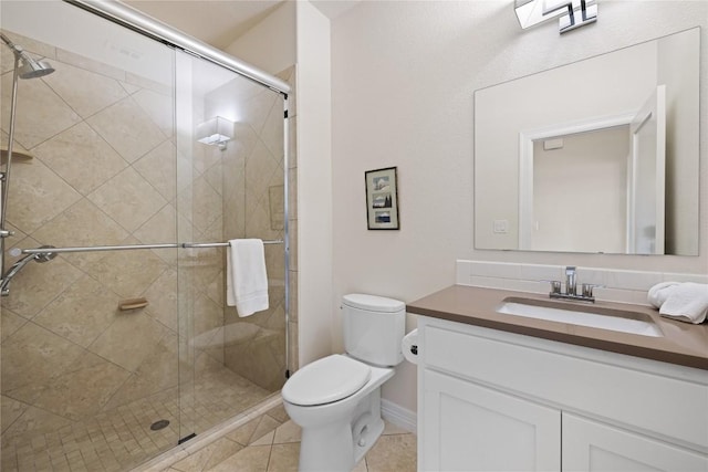 bathroom featuring tile patterned flooring, toilet, vanity, and a stall shower
