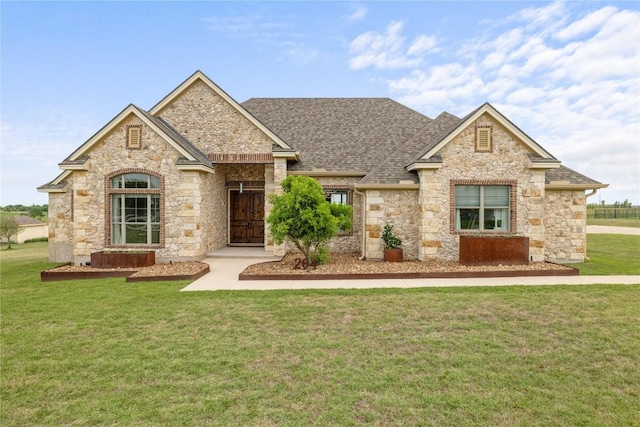 view of front of house featuring a front lawn, stone siding, and a shingled roof