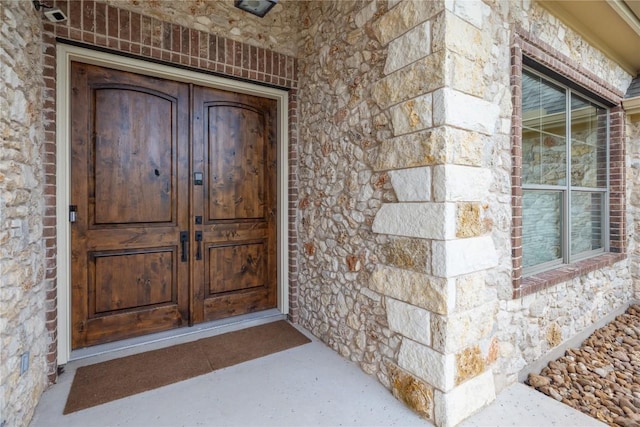 doorway to property featuring stone siding and french doors