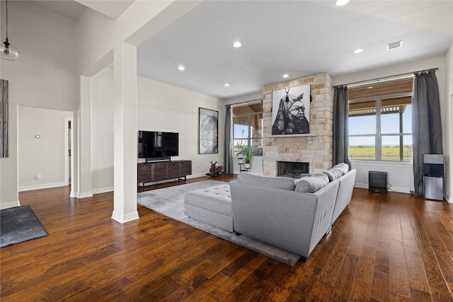 living area featuring recessed lighting, a stone fireplace, visible vents, wood-type flooring, and baseboards