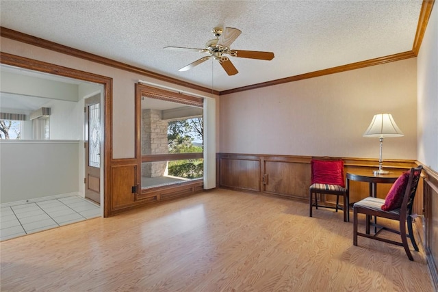 21407 High Dr, Lago Vista, TX 78645 - living area featuring wood finished floors, ceiling fan, a wainscoted wall, a textured ceiling, and ornamental molding