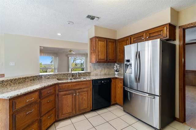 kitchen featuring a sink, brown cabinetry, stainless steel refrigerator with ice dispenser, light stone countertops, and dishwasher